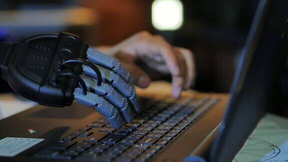 商人戴着假肢在电脑键盘上打字一个年轻人用半机械人的手在笔记本电脑上工作假肢