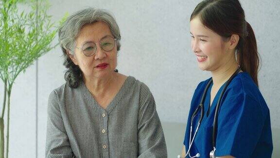 美丽的亚洲护士在医院里微笑着与年长的女病人交谈