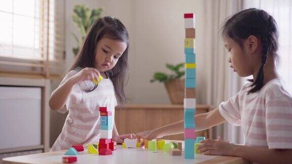 两个女孩喜欢在家里一起玩木制玩具积木