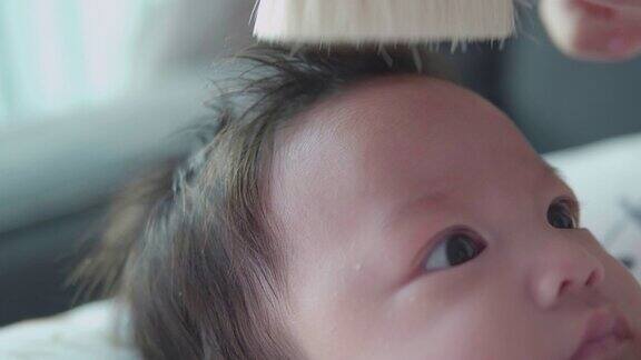 亚洲妇女母亲梳理婴儿的头发