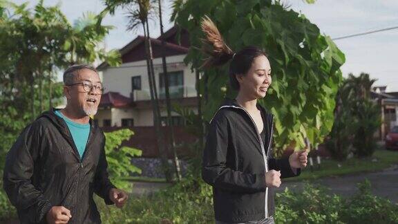 早上一名亚裔中国老人和他的女儿在篮球场打篮球前热身