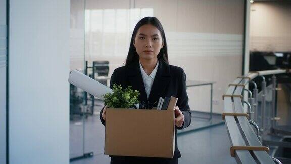 被解雇的亚洲妇女扛着箱子离开室内解雇后的工作场所