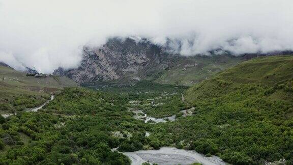 在低地有河流的山谷和覆盖着云的岩石山脉