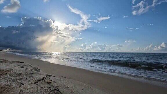 海滩上的地面延时拍摄清晨的太阳在向海岸移动的雷暴后面