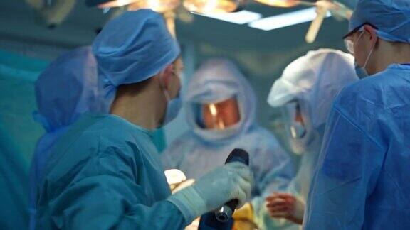 用现代工具进行外科手术一组穿着医疗制服的医生使用医疗设备给病人做手术