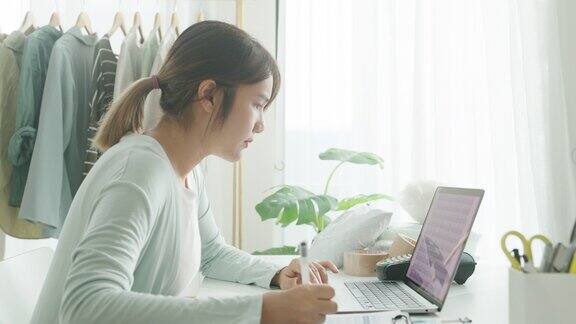 年轻的亚洲女卖家在网上商店工作用笔记本电脑准备包裹准备寄给家里的客户小企业主