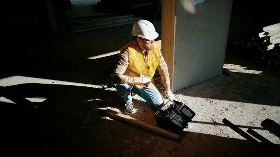 工地上一名建筑工人坐在墙边打开工具箱人类的影子
