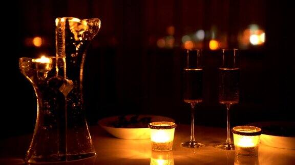 两杯葡萄酒和蜡烛在黑暗中以城市的灯光为背景