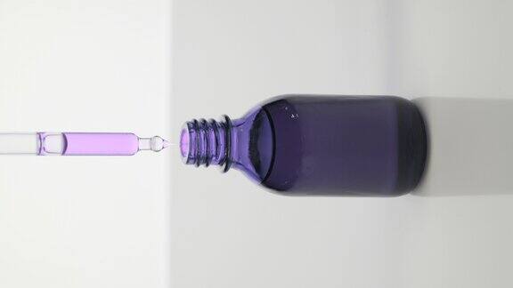 滴管将紫色油滴入灰色背景的紫色瓶中