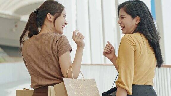 一群年轻的亚洲女人拿着购物袋在百货公司购物朋友们周末在购物中心散步聊天