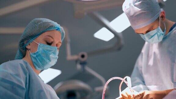 外科医生和护士进行手术专业医生和女助理穿着医疗制服和口罩在诊所操作
