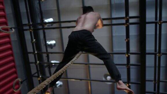下面直接低角度视图极限运动亚洲华人男子运动员攀登绳在健身房