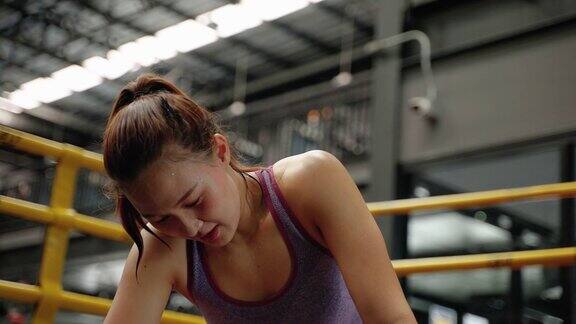 在健身房锻炼后满脸汗水的运动女性疲惫地休息