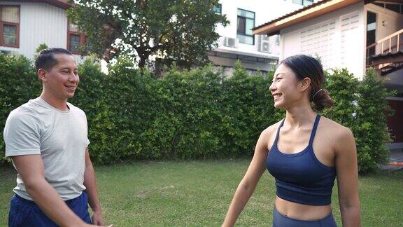 年轻的健身夫妇在花园外击掌亚洲女人和白人男人在公园户外训练