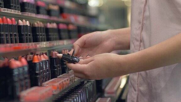 专业女性化妆品买手女为晚妆选择口红在购物中心试用化妆品