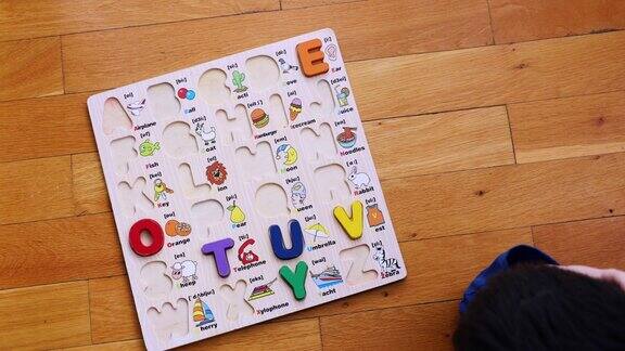 小男孩把字母拼图和学习英语放在地板上