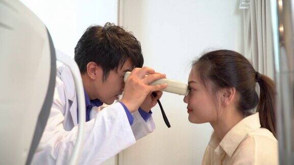 验光师使用眼科仪器对一名年轻女性进行初步眼科健康测试然后使用视力检查表、斯耐伦视力表、侧视图用手动方法进行视力测试