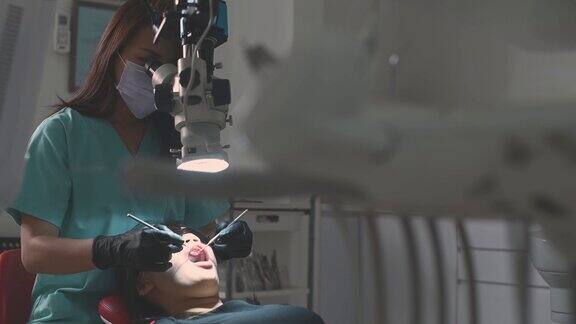 亚洲华裔女牙医在牙医办公室里用显微镜观察病人的牙齿