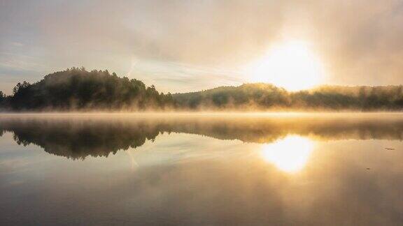 夏天雾蒙蒙的湖面上的日出