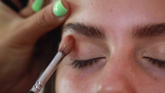 一个美容师用化妆刷涂抹眼影的极端特写