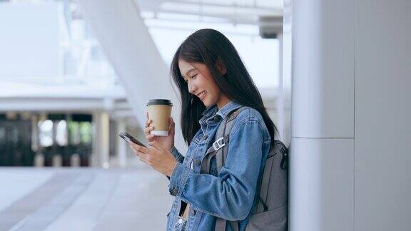 年轻的亚洲女子站在街上使用智能手机