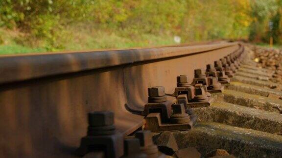 在一个阳光明媚的日子里当缓慢向前从石头的底部看的时候一个大螺钉固定火车轨道的特写