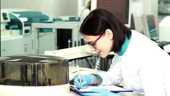 年轻的女化学家在现代实验室做笔记