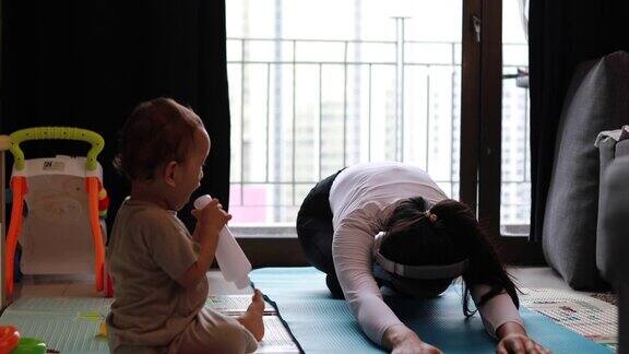 忙碌的妈妈在瑜伽上被宝宝打断的镜头
