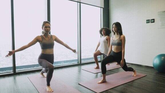 亚洲和非洲裔美国女性朋友一起做瑜伽普拉提锻炼一个女人在健身房和一群人做瑜伽的手的特写