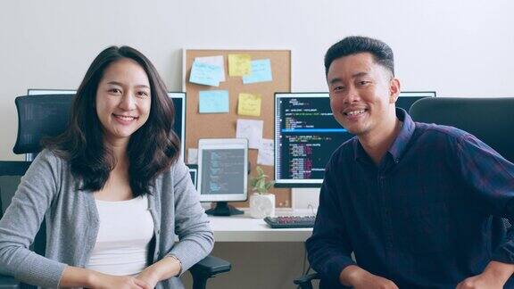 肖像年轻的亚洲女性开发程序员软件工程师IT支持与同事看着相机和微笑一起享受在办公室工作
