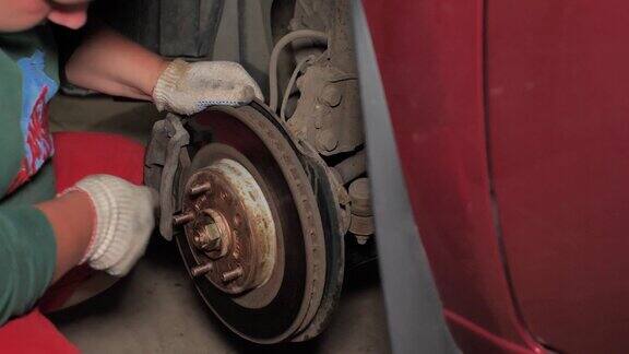 在车库里一个男人正在修理他的汽车轮子一个机械师在车间里自己修车在家修车