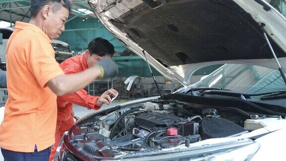 两个汽车修理工都在检查客户送到修理厂修理的汽车的发动机