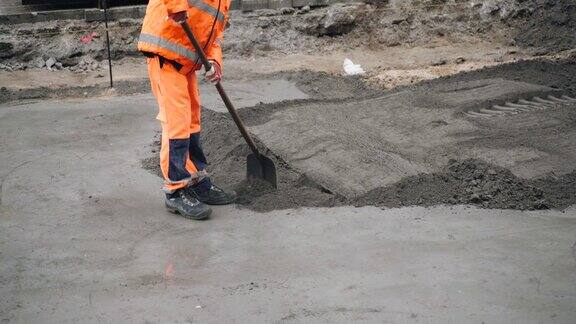 一名筑路工人用铲子把干混凝土摊开