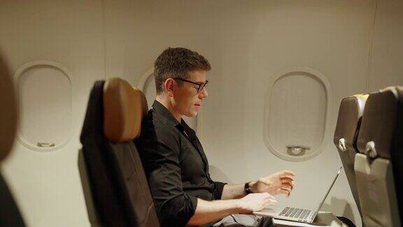 在飞机上旅行时用笔记本电脑工作的4K白人商人