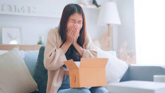 兴奋的年轻亚洲妇女打开纸箱看着里面情绪化的女性惊讶于快速的送货服务快乐的女性客户满意订购