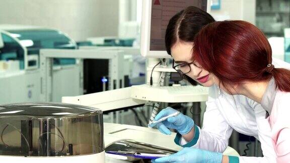 两名女生物学家在做实验时做笔记的特写