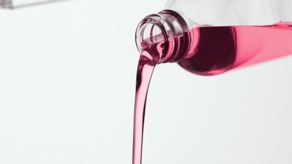试剂瓶倾斜粉红色的油从瓶子里倾泻而出