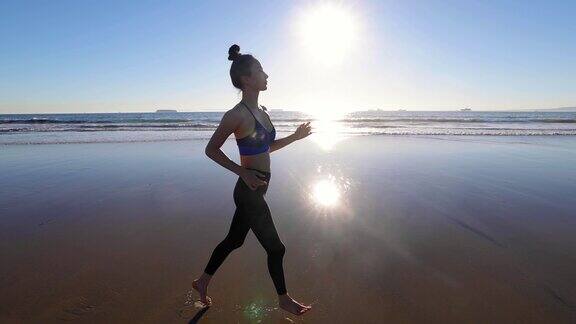 一名亚洲女子在海滩上慢跑的慢动作镜头