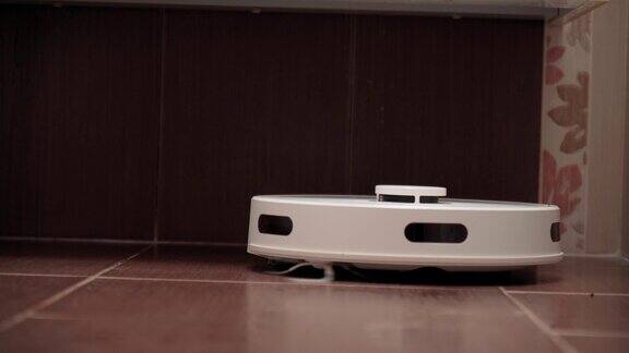 白色智能机器人吸尘器在深色瓷砖地板上清洁浴室有选择性的重点