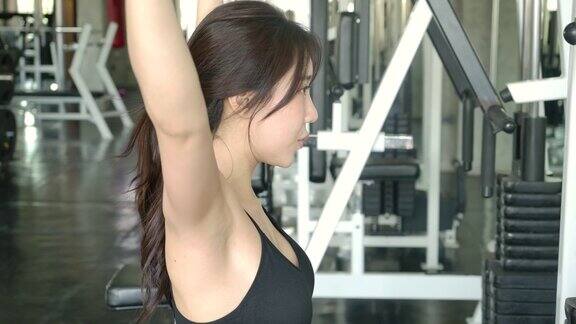 年轻的运动亚洲女人在健身中心的重量机器上锻炼缓慢的运动运动和运动概念