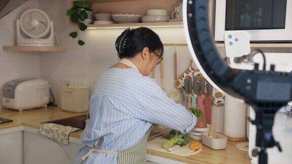 亚洲老年妇女在社交媒体上直播教授烹饪