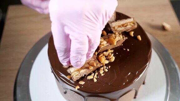 近距离糕点师的手正在用巧克力和花生装饰蛋糕
