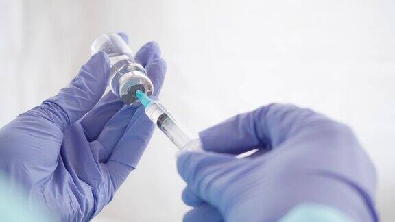 医生的手在医疗手套填充注射器与疫苗从玻璃瓶