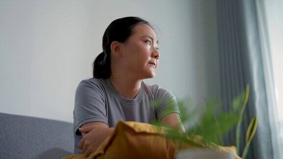 亚洲女人坐在沙发上思考问题感到担忧和困惑