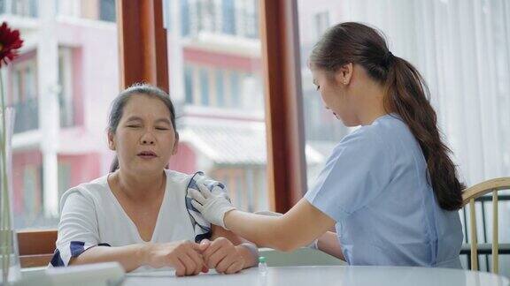 年长的亚洲妇女害怕针头要在自己家里接受疫苗就看护士用医用注射器注射疫苗一位老人被隔离在家里公寓里