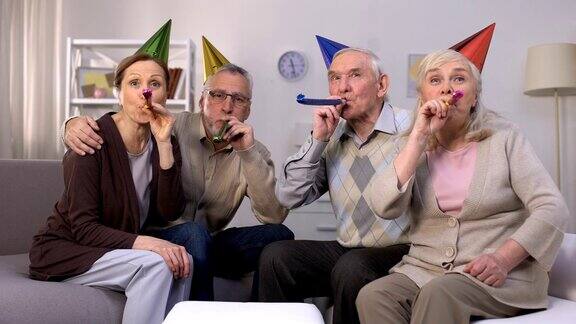 欢天喜地的老人戴着生日帽吹响聚会的号角庆祝聚会