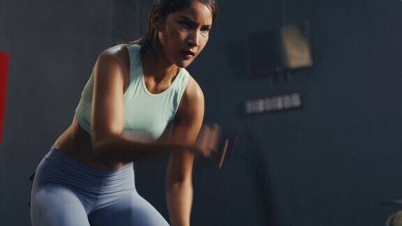 年轻的亚洲女性运动锻炼与战斗绳在健身房力量和动力