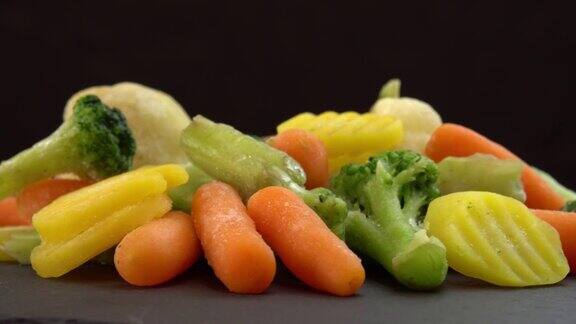 黑色背景是新鲜冷冻蔬菜素食者和纯素食者的健康食品或减肥食品冷冻花椰菜花椰菜和小胡萝卜