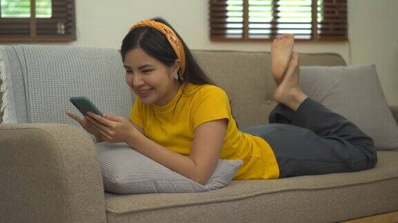 亚洲妇女坐在沙发上使用手机