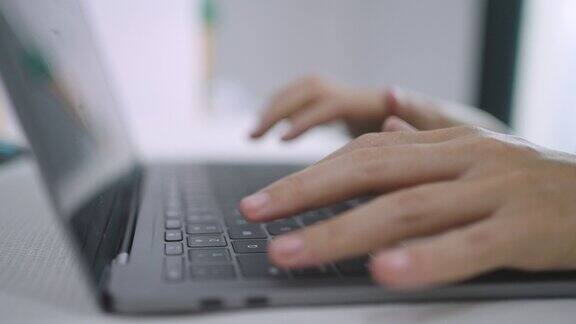 特写女人的手在笔记本电脑键盘上打字